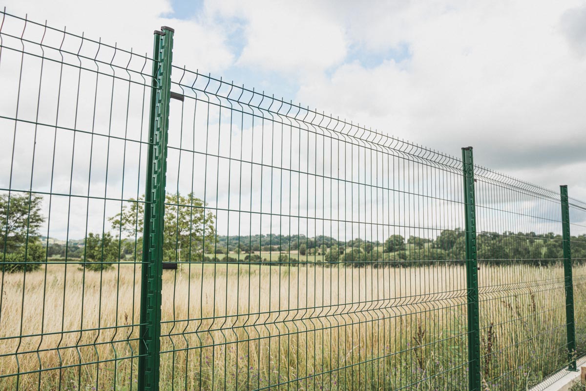 Pose d'une clôture métallique de couleur verte pour l'aménagement extérieur d'un poulailler réalisé en béton